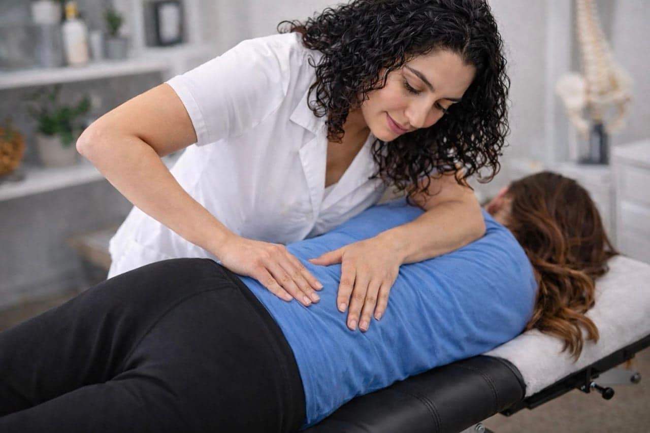 Dr. Tina Navarifar performing a chiropractic adjustment on a patient lying face down on a treatment table